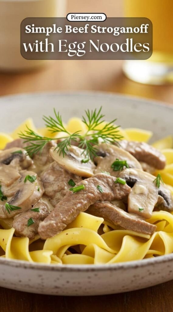 A close-up of a bowl of beef stroganoff with egg noodles, garnished with fresh herbs. The dish looks creamy and savory, evoking warmth and comfort.