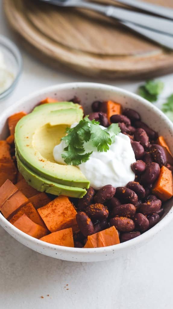 A colorful sweet potato and black bean breakfast bowl topped with avocado and lemon.