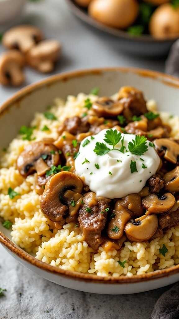 A bowl of keto beef stroganoff served over cauliflower rice with mushrooms and topped with sour cream.