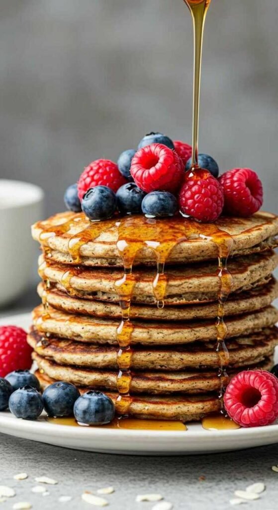 A stack of coconut flour pancakes topped with fresh berries and syrup.