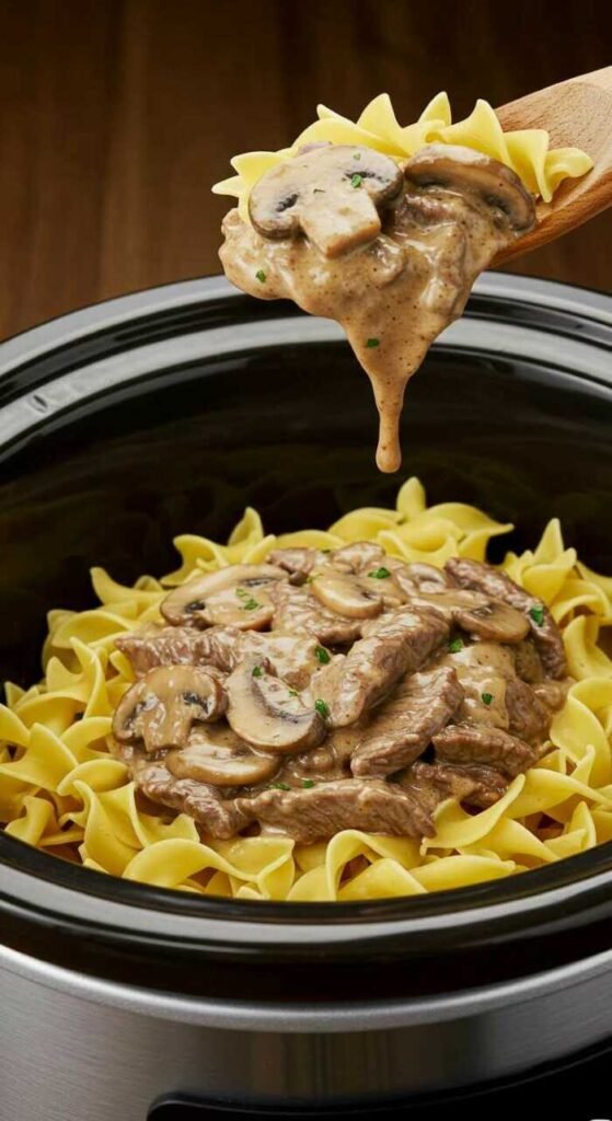 A delicious looking beef and mushroom stroganoff over noodles in a crockpot.