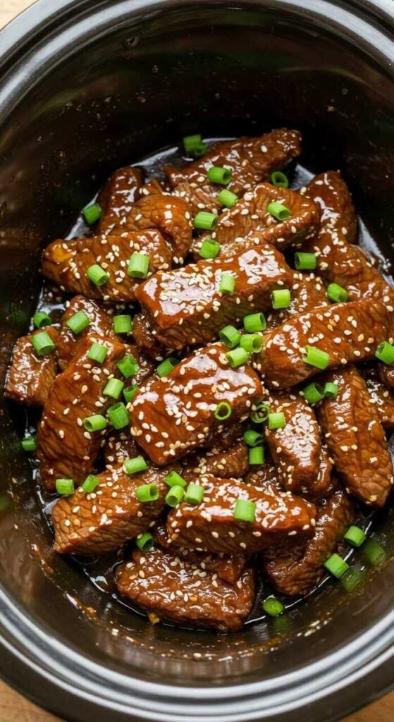 A bowl of Teriyaki Beef with sesame seeds and green onions, perfect for a slow cooker recipe.