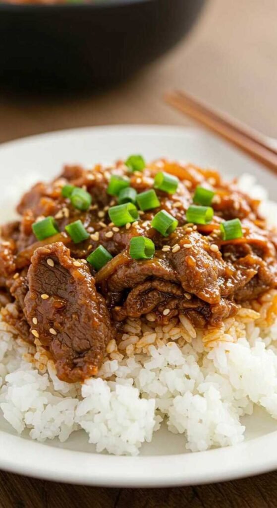 A plate of Korean Beef Bulgogi garnished with green onions and served with rice.