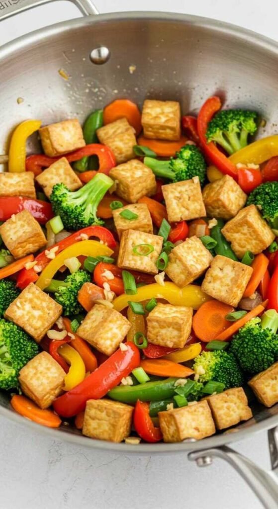A colorful vegetable stir-fry with tofu in a pan, surrounded by fresh vegetables.