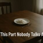 The Hardest Thing About the Rice Diet May Surprise You A single plate of rice and a fork sit on a wooden table in dim light, evoking simplicity and solitude. The text reads, "This Part Nobody Talks About."