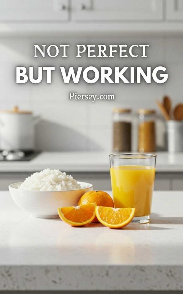 A bowl of white rice, sliced oranges, and a glass of orange juice on a kitchen counter. Text above reads, "Not perfect but working." Bright and inviting tone.